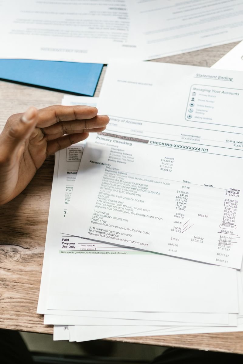 Hands holding financial documents with calculator and laptop on office desk, business analysis scene.